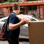 A professional mover handing a box that contains clothing