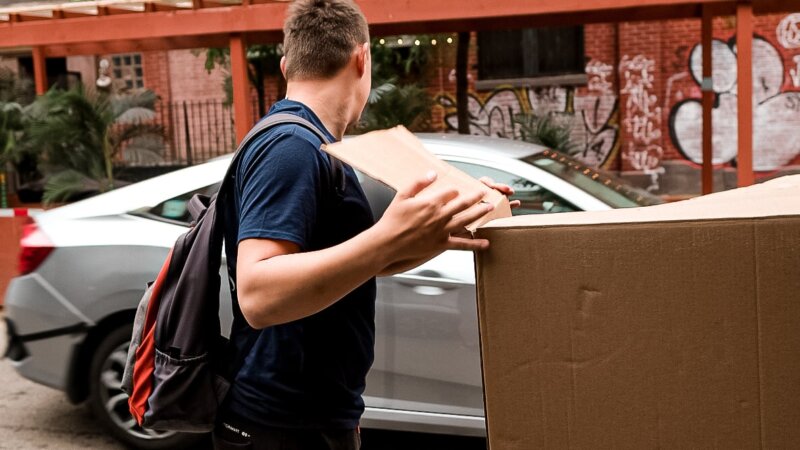 A professional mover handing a box that contains clothing