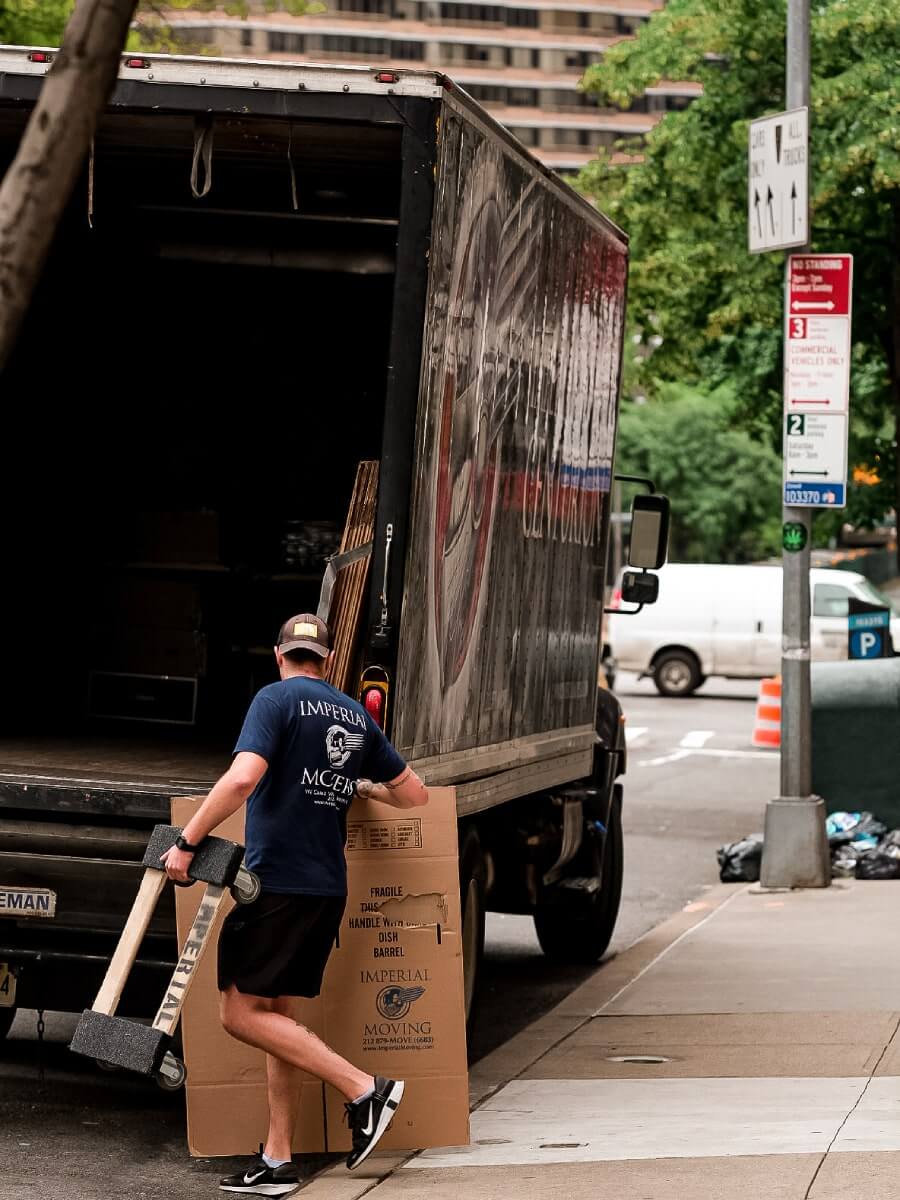 A mover carrying moving equipment and boxes to an empty moving truck