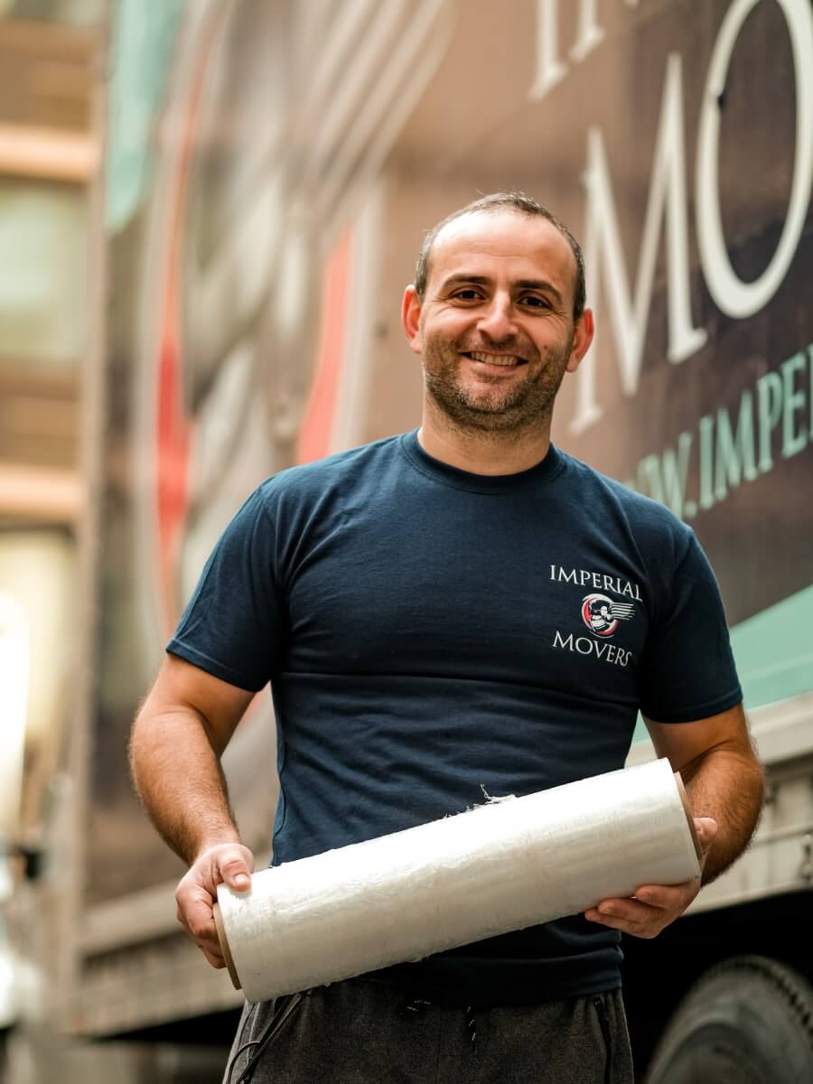 A smiling man holding a roll of moving plastic