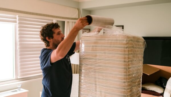 A professional mover wrapping a large item in plastic