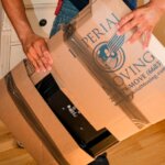 A professional mover wrapping an electronic appliance with boxes