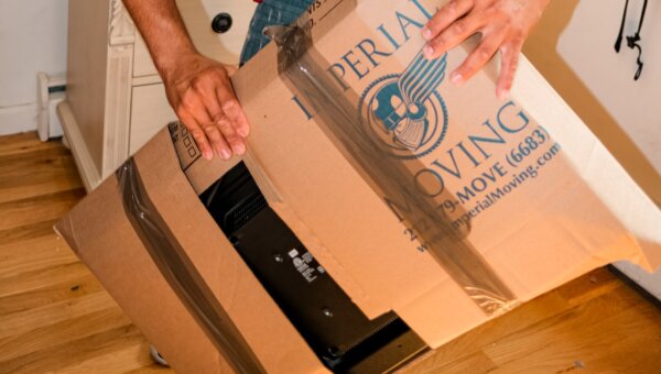 A professional mover wrapping an electronic appliance with boxes