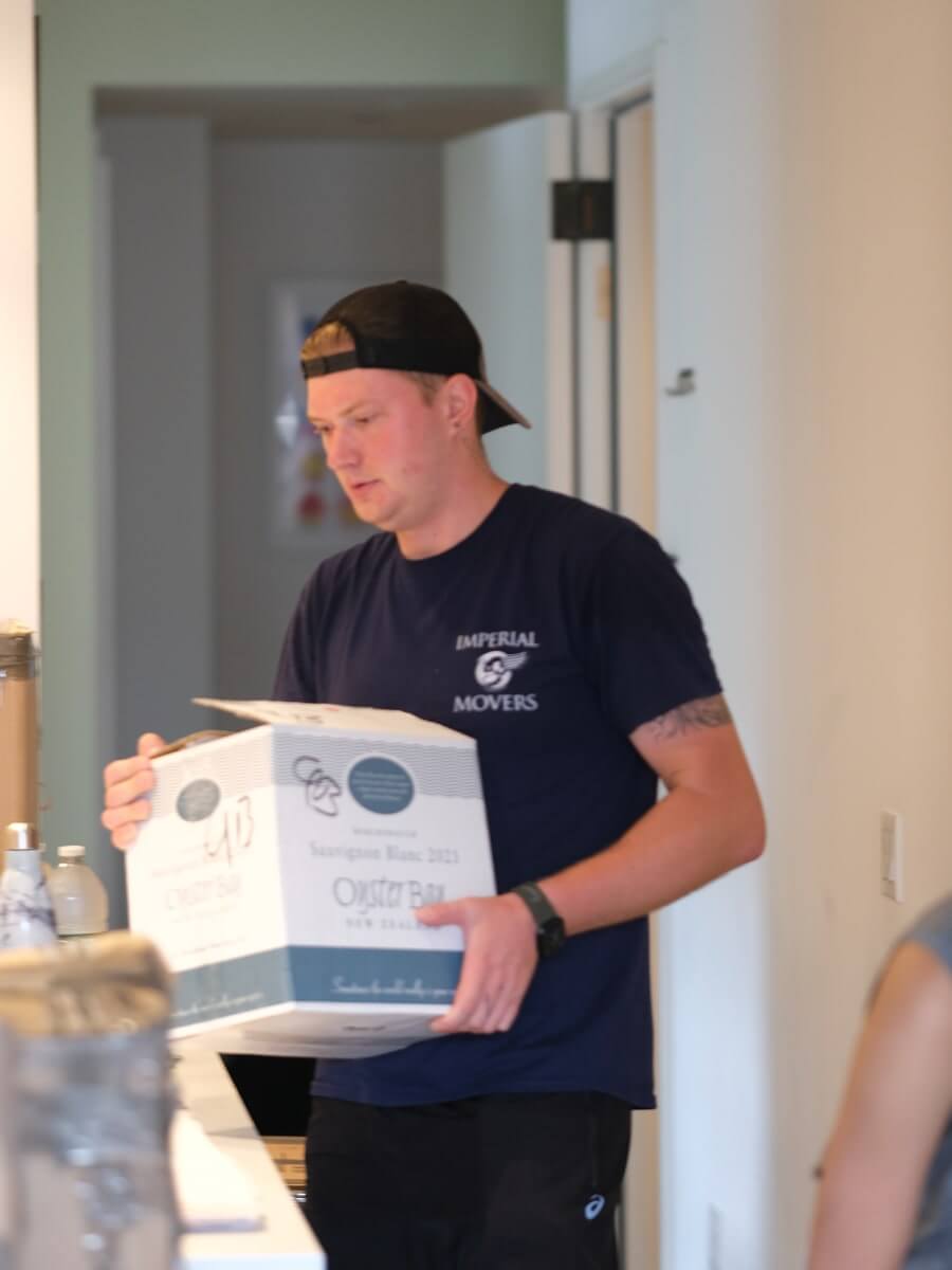 A man carrying a wine box through a well-lit house